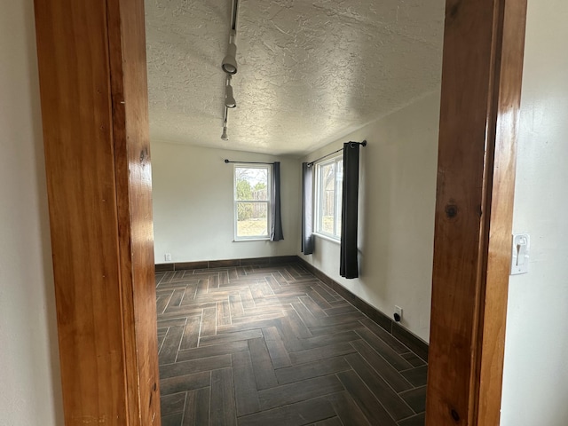 spare room with a textured ceiling and baseboards