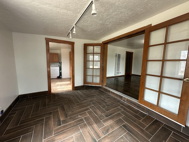 spare room with track lighting, baseboards, and a textured ceiling