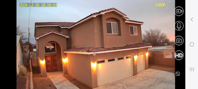 mediterranean / spanish house with stucco siding, concrete driveway, a tile roof, and a garage