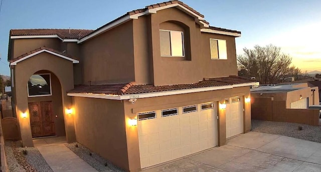 view of front of home featuring stucco siding, concrete driveway, an attached garage, and a tile roof