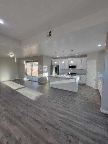 kitchen featuring fridge, stainless steel microwave, recessed lighting, open floor plan, and white cabinets