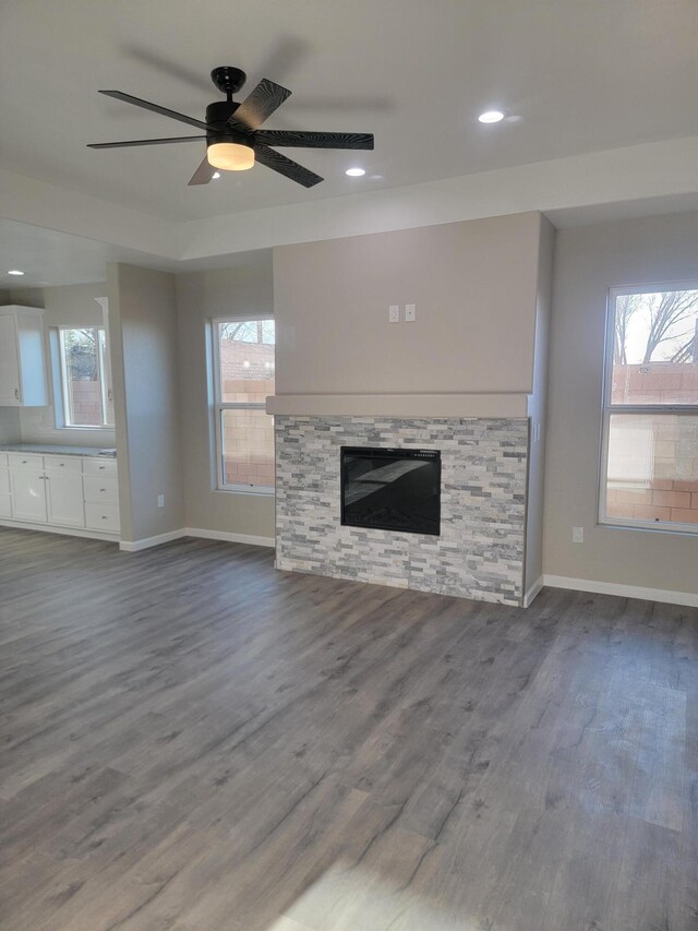 unfurnished living room featuring a ceiling fan, wood finished floors, a fireplace, and baseboards