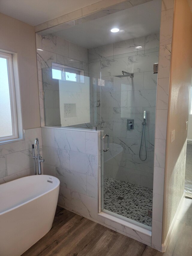 bathroom with a marble finish shower, a wealth of natural light, a freestanding tub, and wood finished floors