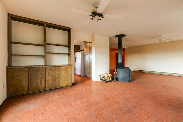 unfurnished living room featuring a wood stove, baseboard heating, and ceiling fan