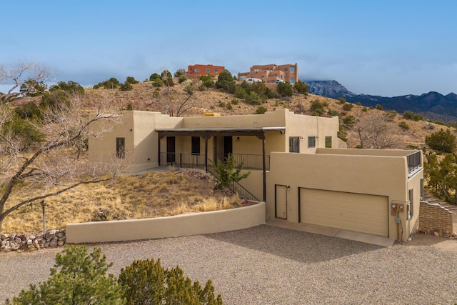 pueblo revival-style home with a garage, a mountain view, and stucco siding