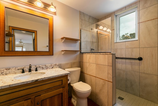 bathroom featuring tile walls, vanity, tiled shower, and toilet