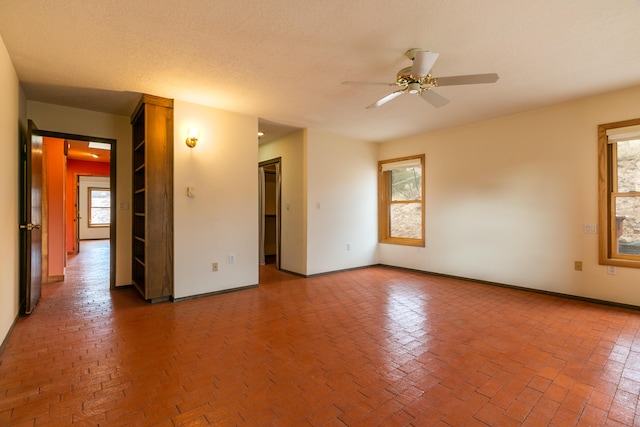 unfurnished room with ceiling fan and a textured ceiling