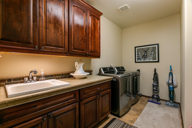 clothes washing area with cabinet space, baseboards, visible vents, washing machine and clothes dryer, and a sink