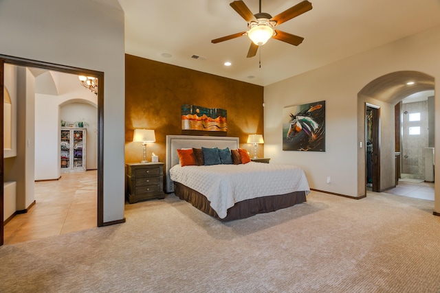 bedroom with light carpet, arched walkways, visible vents, and baseboards