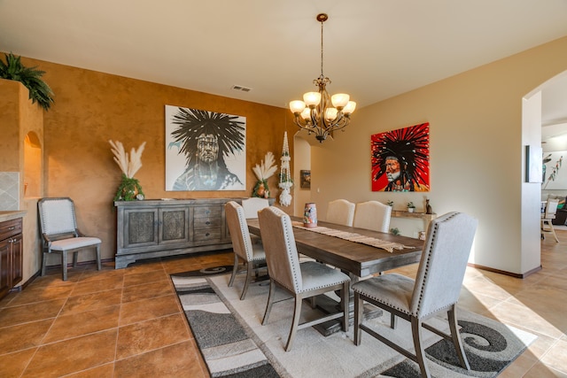 dining space featuring light tile patterned floors, visible vents, arched walkways, baseboards, and a notable chandelier