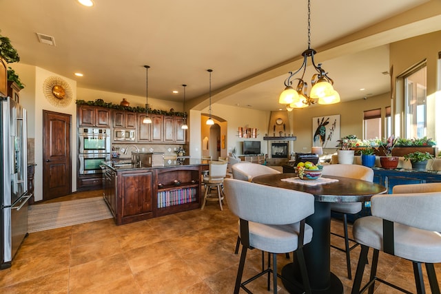 kitchen featuring arched walkways, stainless steel appliances, dark countertops, open floor plan, and a kitchen island with sink