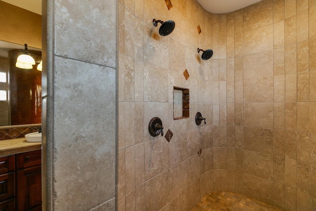 full bathroom with a tile shower and vanity