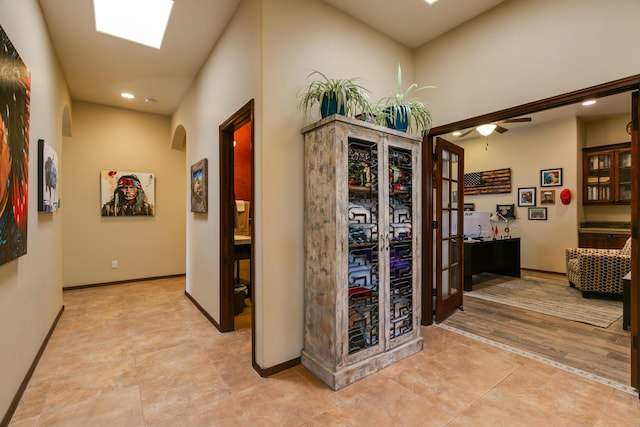 hallway featuring arched walkways, baseboards, and recessed lighting