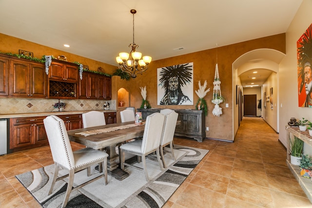 dining area featuring arched walkways, recessed lighting, and an inviting chandelier