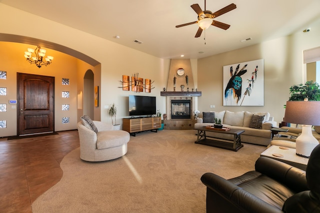 living area featuring visible vents, arched walkways, a multi sided fireplace, and ceiling fan with notable chandelier