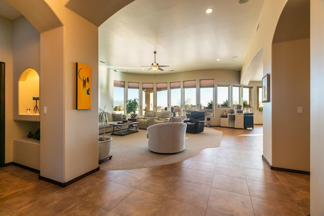 tiled living room featuring baseboards, arched walkways, a ceiling fan, and recessed lighting