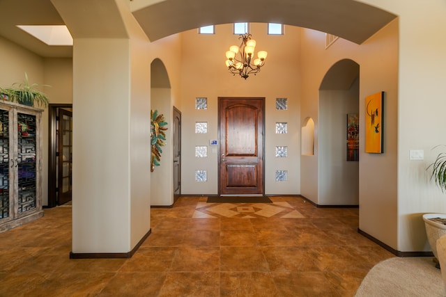 entrance foyer featuring baseboards, a towering ceiling, and an inviting chandelier