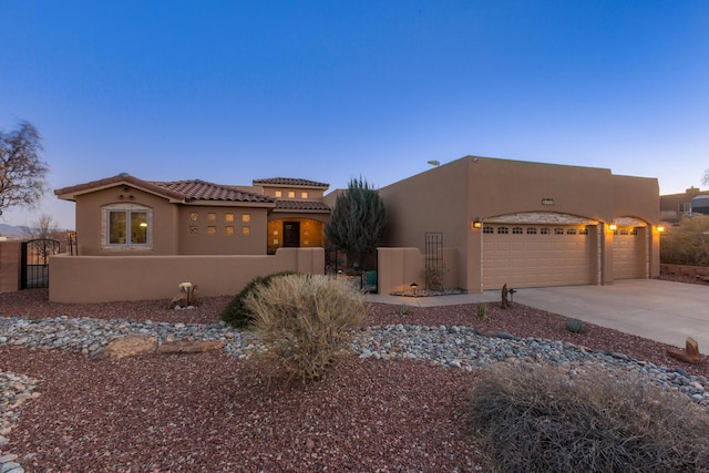 view of front of house with a garage, driveway, a fenced front yard, and stucco siding