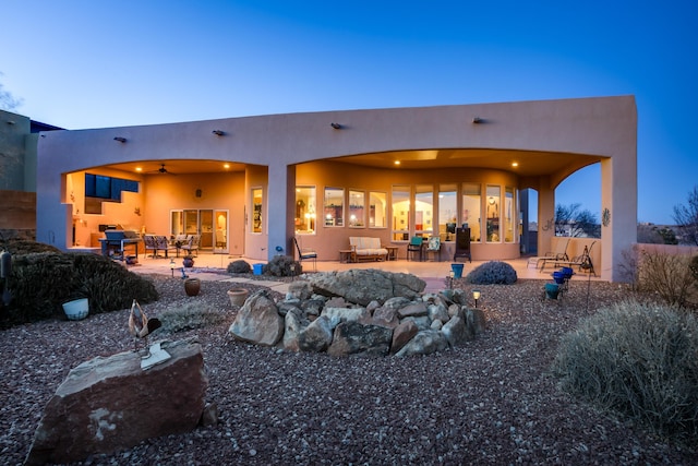 rear view of house with ceiling fan, a patio, an outdoor hangout area, and stucco siding