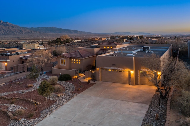 southwest-style home featuring concrete driveway, a fenced front yard, an attached garage, a mountain view, and stucco siding