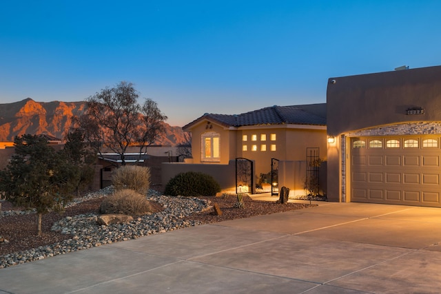 view of front of property featuring a fenced front yard, a tile roof, stucco siding, concrete driveway, and a garage