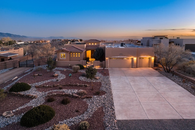 adobe home with a garage, driveway, fence, and stucco siding