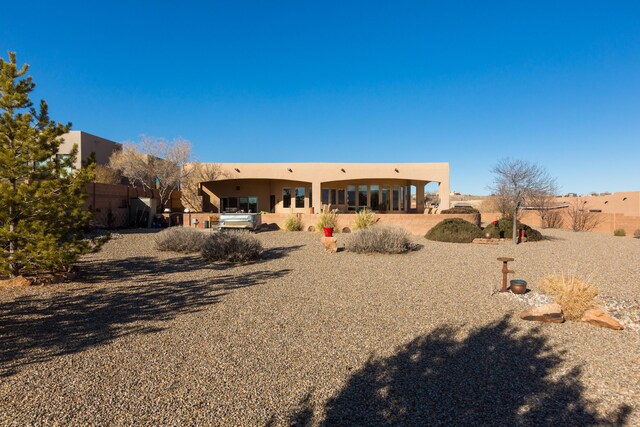 rear view of house with stucco siding, a patio, and fence