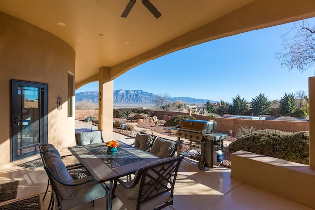 view of patio featuring a mountain view, outdoor dining area, a ceiling fan, and area for grilling