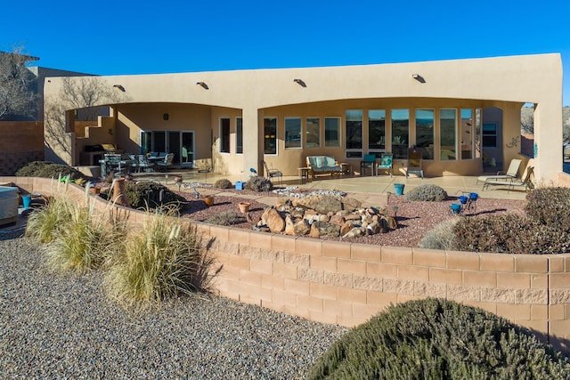 rear view of house with a patio area and stucco siding