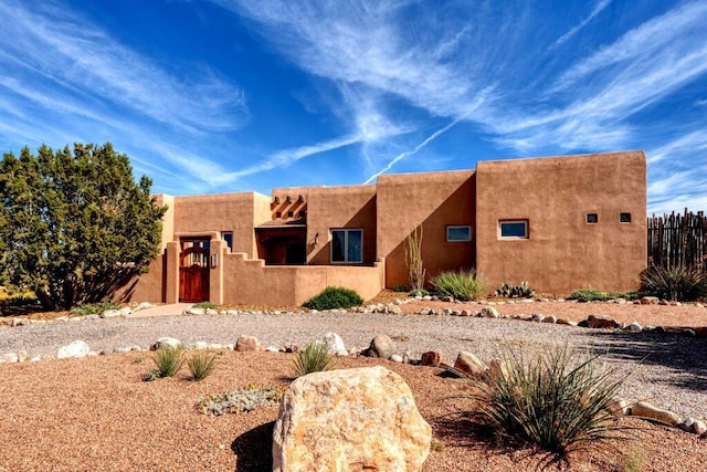 pueblo-style home featuring fence private yard