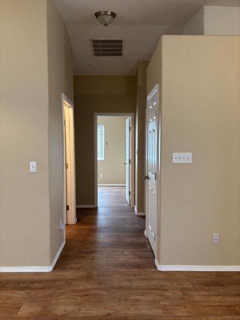 hallway featuring dark wood-style floors, baseboards, and visible vents