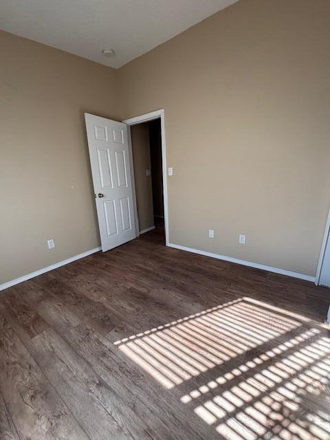 unfurnished room with baseboards and wood finished floors