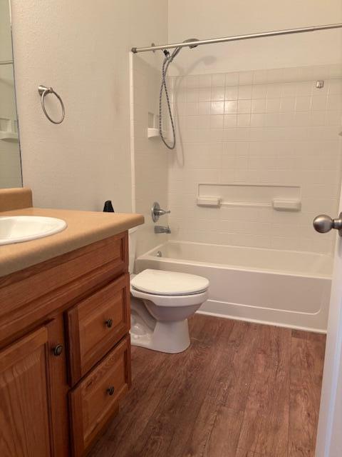 bathroom featuring tub / shower combination, vanity, toilet, and wood finished floors