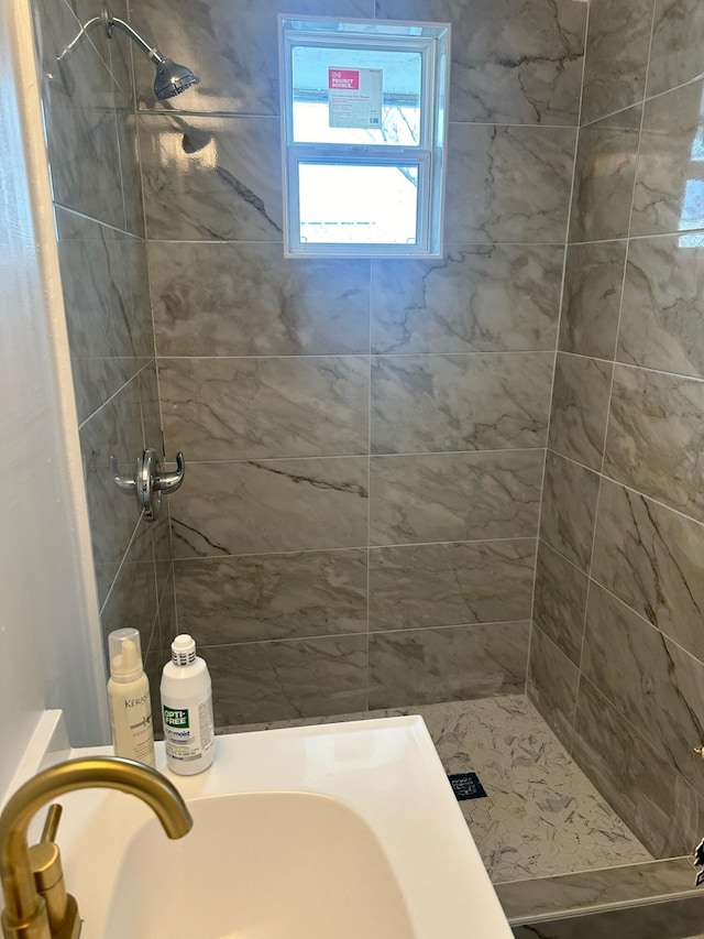 bathroom with a tile shower and a sink