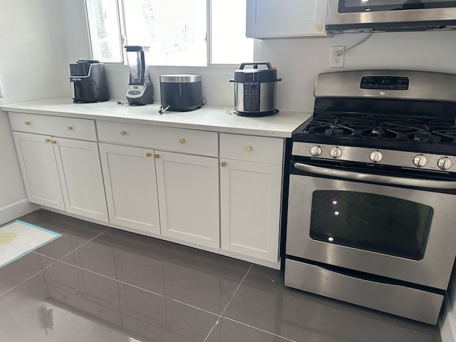 kitchen featuring stainless steel appliances, tile patterned flooring, light countertops, and white cabinetry