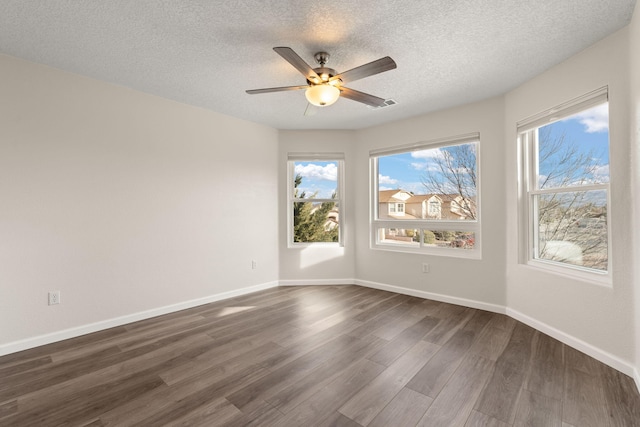 spare room with dark wood-style floors, ceiling fan, a textured ceiling, and baseboards