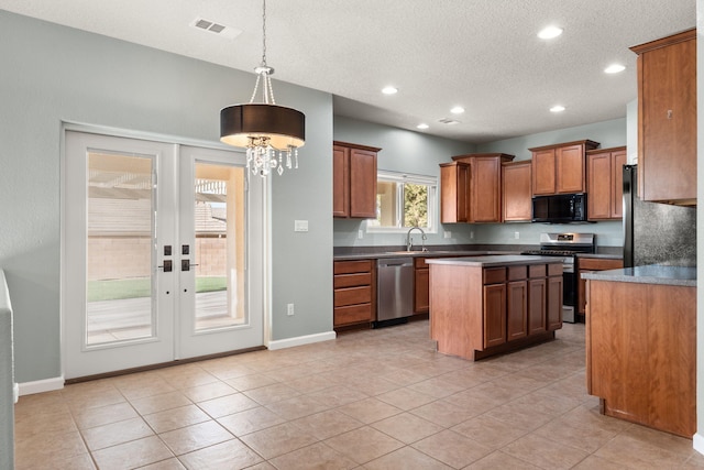 kitchen with dark countertops, visible vents, appliances with stainless steel finishes, and hanging light fixtures