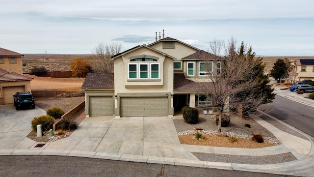 traditional home featuring driveway, an attached garage, and stucco siding