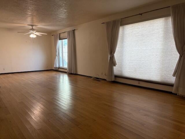 empty room with ceiling fan, dark wood-type flooring, a baseboard radiator, and a textured ceiling