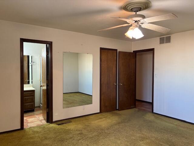 unfurnished bedroom featuring connected bathroom, light colored carpet, a closet, and ceiling fan