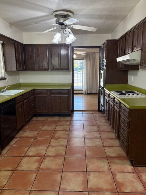 kitchen featuring light tile patterned flooring, sink, black appliances, dark brown cabinets, and a textured ceiling