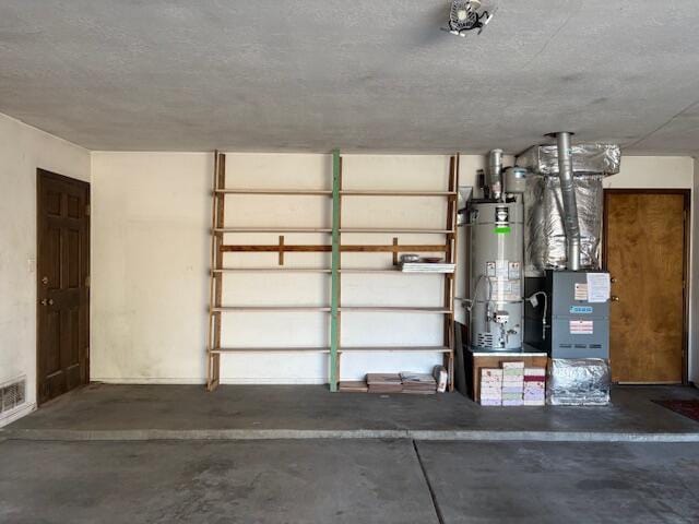 garage featuring heating unit and strapped water heater