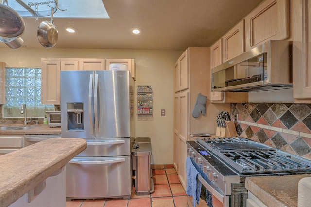 kitchen featuring sink, light tile patterned flooring, white cabinetry, stainless steel appliances, and decorative backsplash