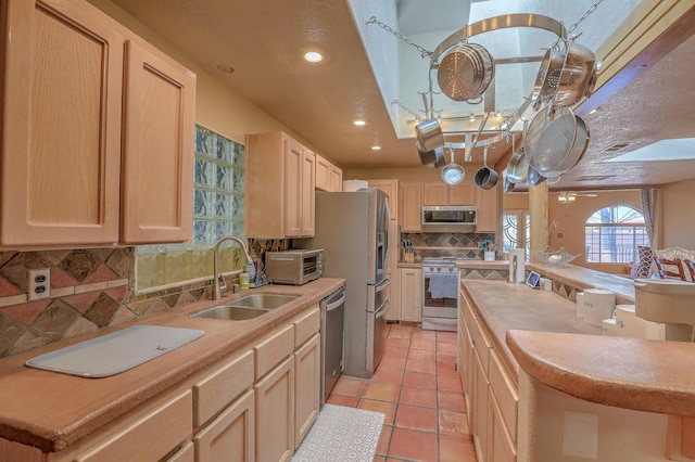 kitchen with light tile patterned floors, stainless steel appliances, light brown cabinets, and sink