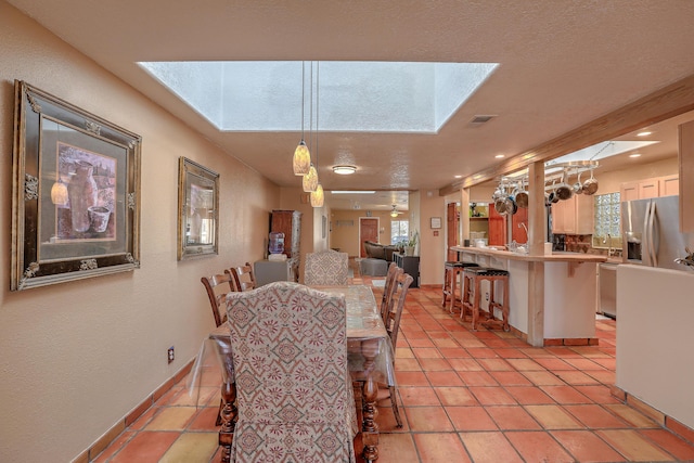 dining area featuring a textured ceiling, a skylight, and light tile patterned floors