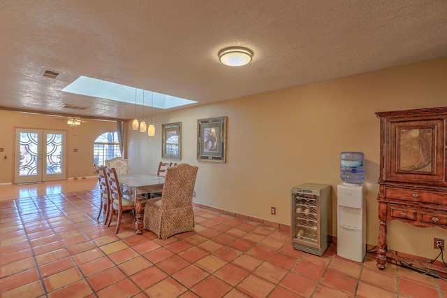 tiled dining area featuring heating unit, a textured ceiling, and a skylight