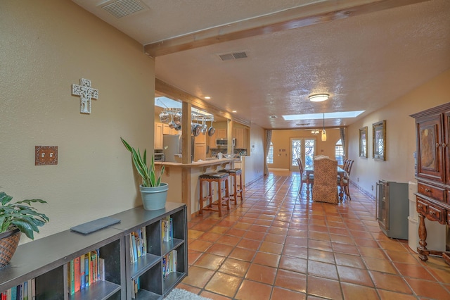 interior space with light tile patterned floors, a skylight, and a textured ceiling