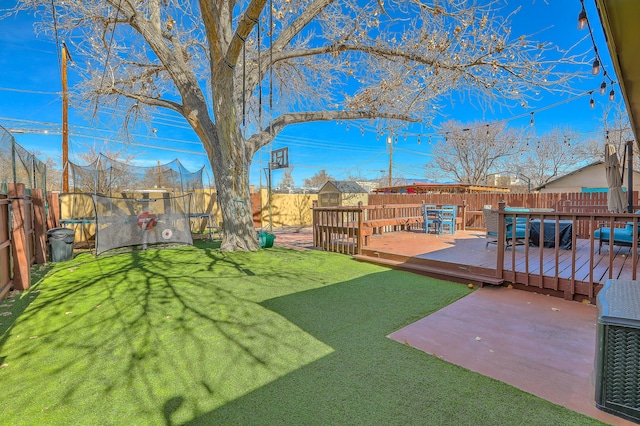 view of yard with a trampoline and a wooden deck