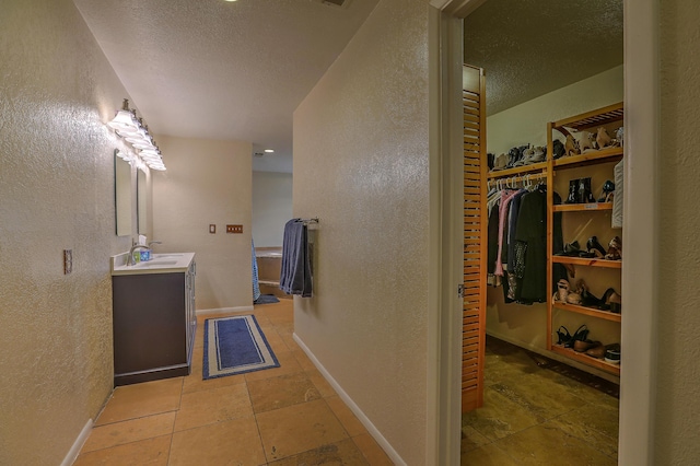 bathroom with a textured ceiling, vanity, and tile patterned floors