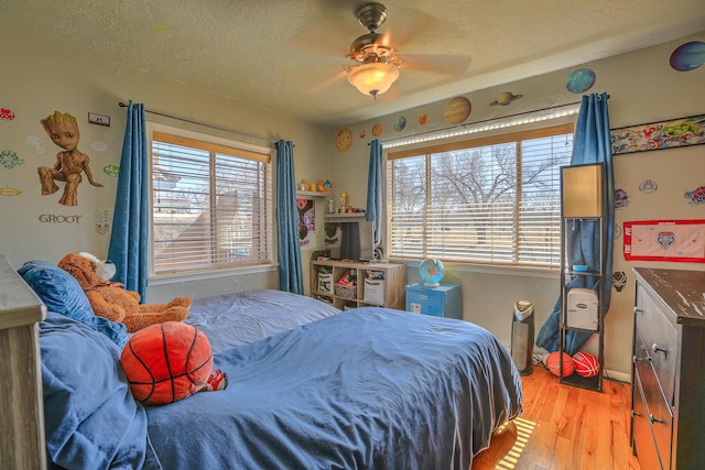 bedroom featuring light wood-type flooring, ceiling fan, and a textured ceiling